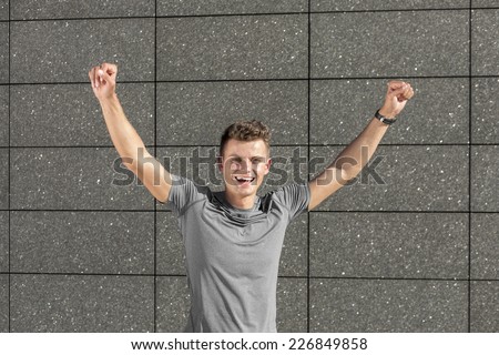 Portrait of successful male jogger with clenched fist against tiled wall