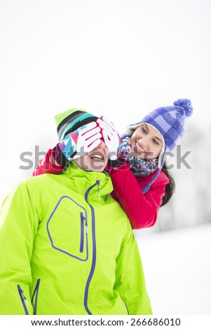 Smiling young woman covering man\'s eyes in winter