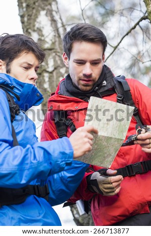 Male backpackers reading map together in forest