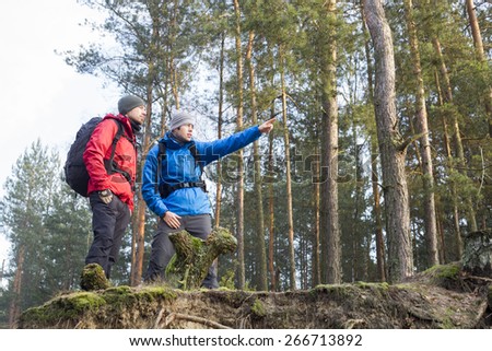 Young male hiker showing something to friend in forest