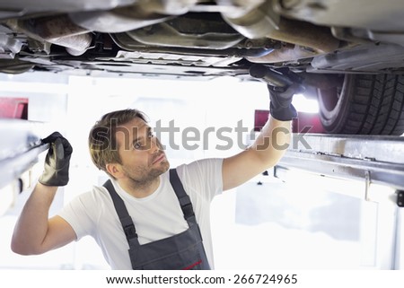 Male repair worker examining car in workshop
