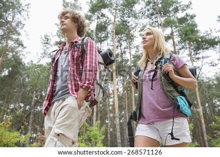 Low angle view of hiking couple looking away in forest