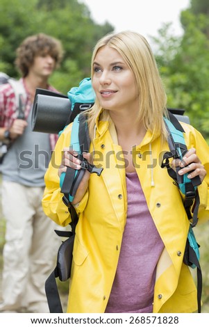 Female backpacker with man standing in background at forest