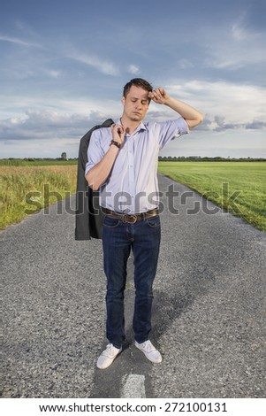 Full length of tired young man standing on empty rural road