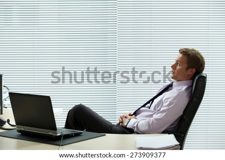 Businessman relaxing on chair with laptop on desk