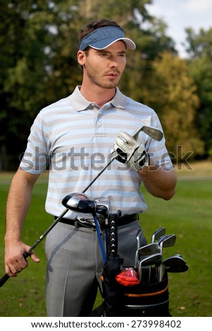 Young man standing by golf bag full of sticks
