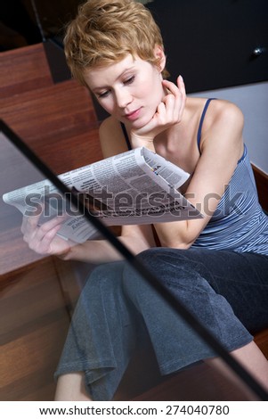 Woman reading newspaper on stairs