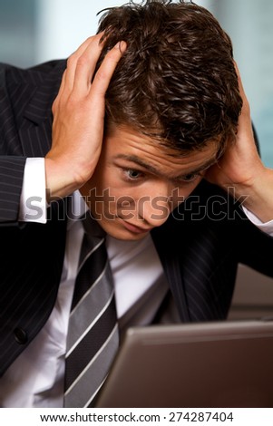 Businessman using laptop with head in hands