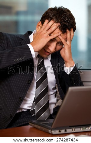 Businessman using laptop with head in hands
