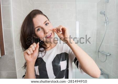 Portrait of young woman flossing teeth in bathroom