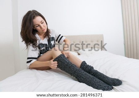 Full length of young woman wearing socks in bed