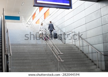 Rear view of businesspeople with luggage moving upstairs in railroad station