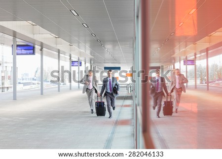 Full length of businessmen with luggage rushing on railroad platform