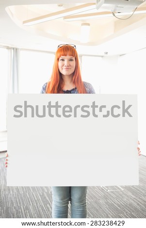 Portrait of confident businesswoman holding blank placard in creative office