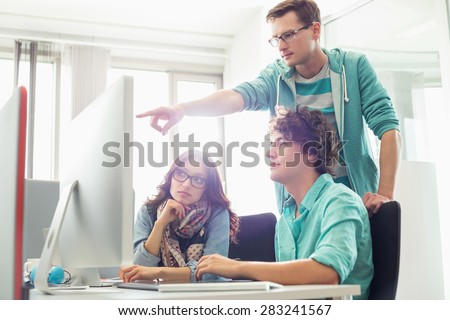 Businessman showing something to colleagues on computer in creative office