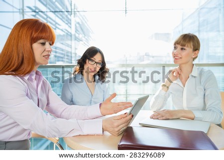 Businesswomen discussing over table PC at table in office