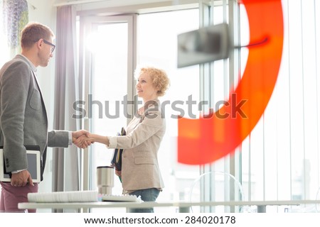Creative business colleagues shaking hands in office