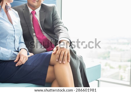 Midsection of businessman flirting with female colleague in office