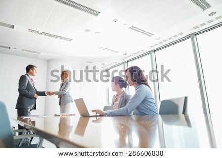 Businesspeople shaking hands in board room
