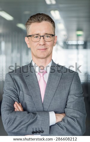 Portrait of middle-aged businessman standing with arms crossed in office