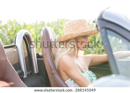 Side view of woman driving convertible outdoors