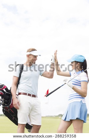 Happy male and female friends giving high-five at golf course