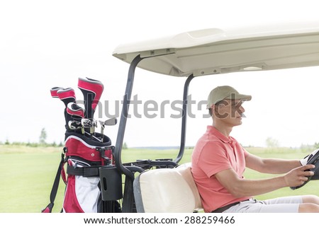 Middle-aged man driving golf cart at course