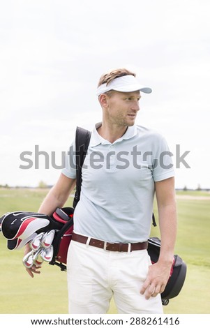 Thoughtful mid-adult man carrying golf club bag against clear sky