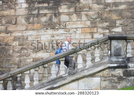 Side view of middle-aged couple climbing steps outside old building