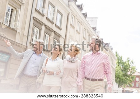 Middle-aged man showing something to friends while walking in city