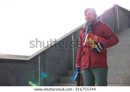 Smiling man holding gifts while moving down steps