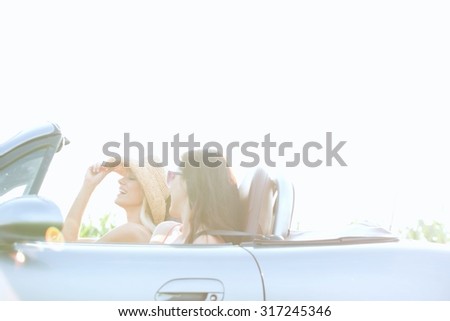 Happy female friends enjoying road trip in convertible on sunny day