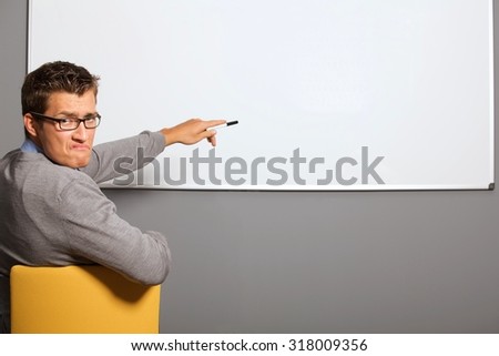 Portrait of businessman pointing at whiteboard and making face in office