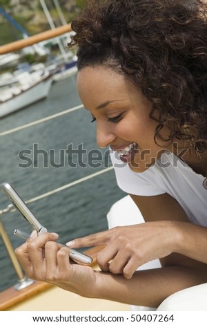 Woman lying on yacht, using mobile phone, (close-up)
