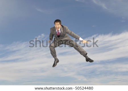 Business man crouching mid-air outdoors