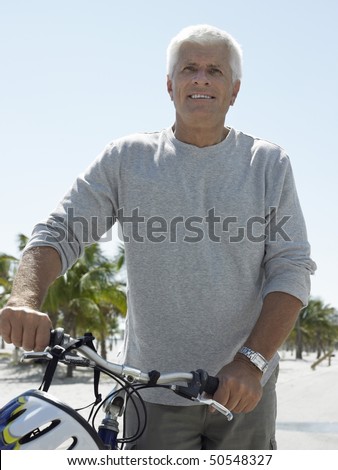 Smiled senior man on bicycle on tropical beach
