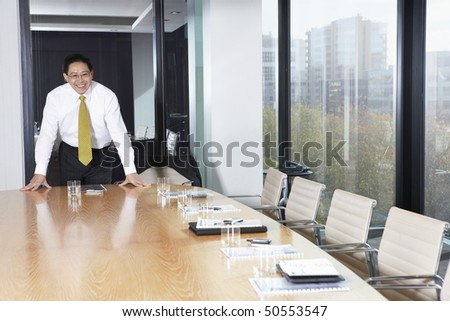 Business man standing behind table in boardroom