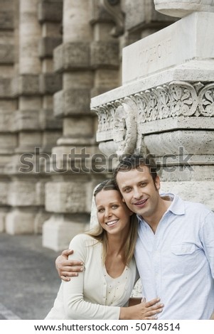 Couple by building pillars in Rome, Italy, portrait