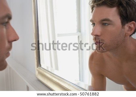 Man examining reflection in mirror