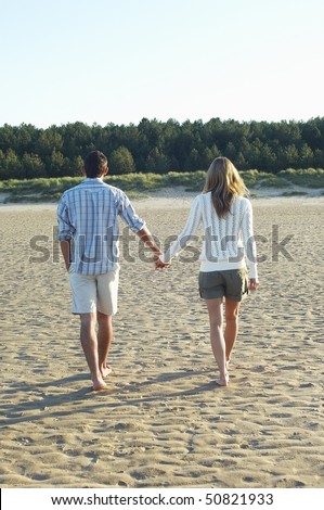Couple Walking on Beach holding hands, back view