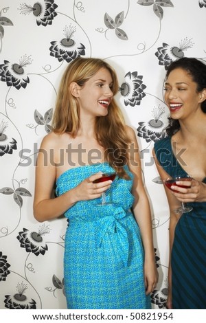 Two women Drinking Martinis by floral print wall
