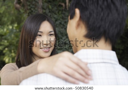 Woman and man standing outside Looking at each other, hand on shoulder