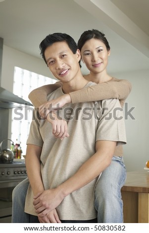 Wife sitting on countertop, arms around standing husband