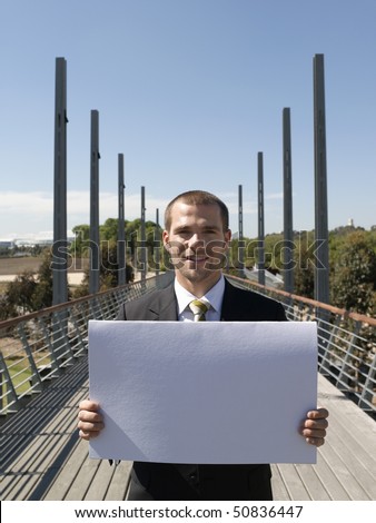 Young business man standing on bridge holding papers