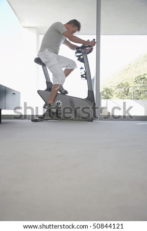 Mature man on exercise bike, pedalling, side view