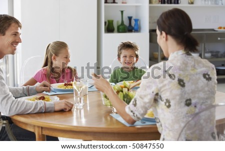 Family eating dinner at round table, in kitchen