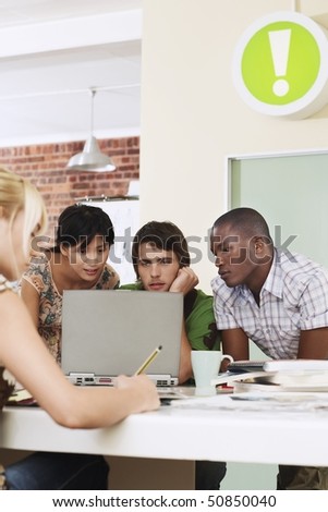 Four people having meeting around laptop.