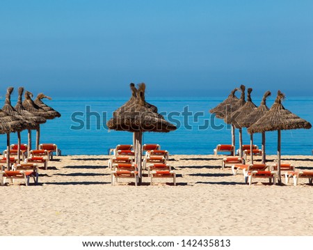Tropical beach scenery with parasol and deck chairs.  umbrella and deck chairs