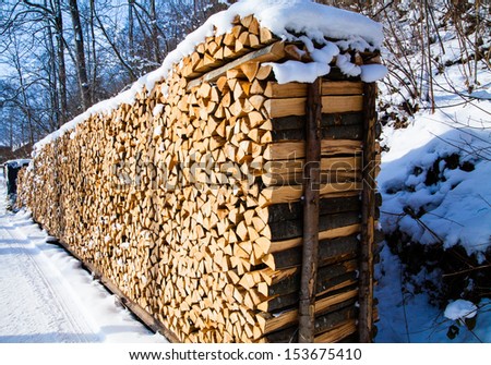 Firewood stacked in winter. Wood pile with snow stacked for firewood
