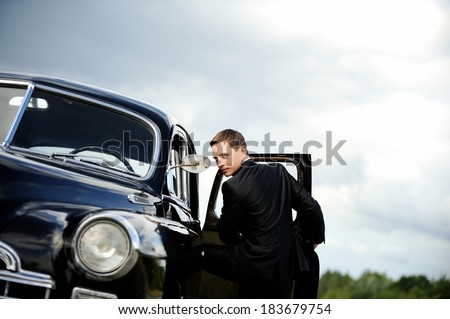 Cool guy getting into his vintage car and looking at the camera.
